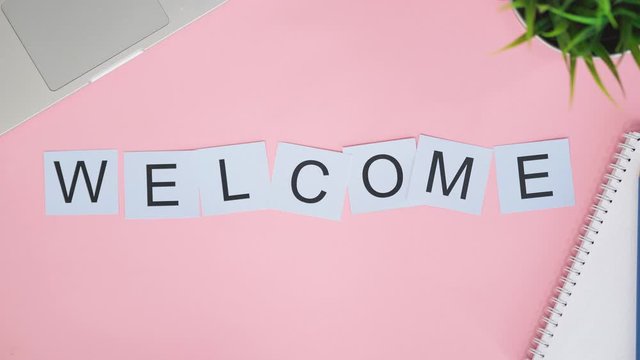 Top view time lapse letters cards laying on pink desk. Word WELCOME