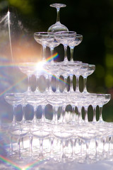 Champagne glasses are displayed in a pyramid. Wedding day, field registration of the engagement, shimmer in the sun.