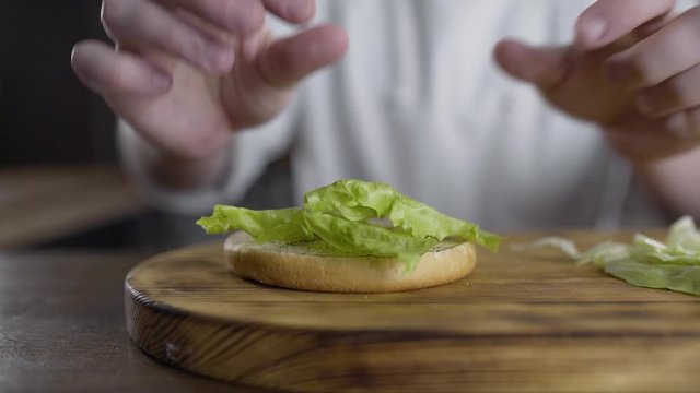 shef povar gotovit na kukhne na otkrytom ogne gotovit burger, vykladyvayet ovoshi na burger, prigotovleniye burgera na kukhne
the chef cooks in the kitchen on an open fire preparing a burger, puts ve