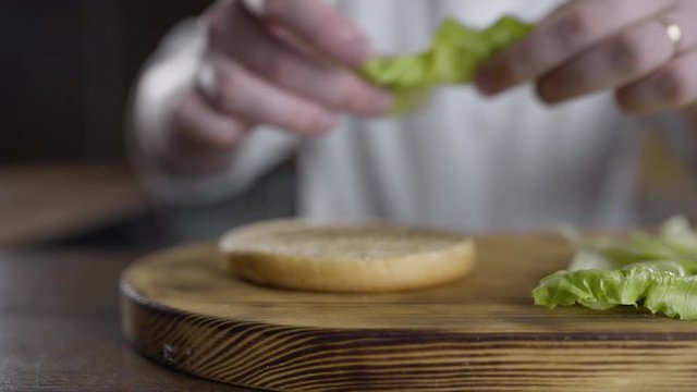 shef povar gotovit na kukhne na otkrytom ogne gotovit burger, vykladyvayet ovoshi na burger, prigotovleniye burgera na kukhne
the chef cooks in the kitchen on an open fire preparing a burger, puts ve