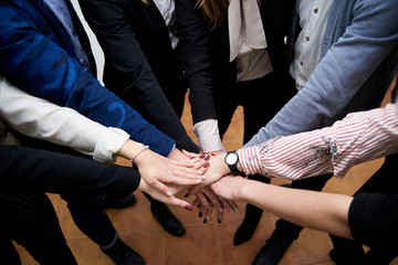 Team building process in company with young progressive people. Work meeting in office that include voting and making decision. Hands of people, held together in the middle.
