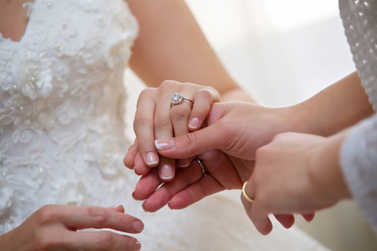 A mother's hand holds the hand of her daughter in the image of a bride.