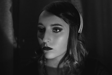 Black and white portrait of a young woman in the style of the 20s. Vintage makeup and hairstyle.