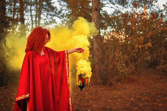 Smoke screen in the woods. Woman with smoke. Beautiful woman with yellow smoke behind her in the forest