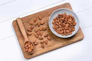 Whole almond nuts on old wooden table with wooden spoon