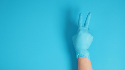 Hand with glove doing Peace or Good Luck sign.It is hand gesturing two finger on blue background.
