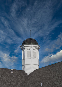 An Old White Wod Cupola On A Shingled Roof Under Clear Blue Sky