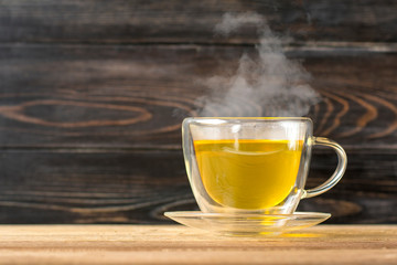 glass transparent cup of hot green tea with steamon wooden table Healthy drink, antistress beverage concept