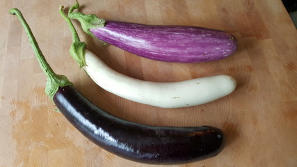 3 multi colored eggplant on a cutting board