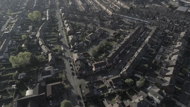 Aerial view flying above suburban British housing rooftops at sunrise golden hour birds eye orbit left