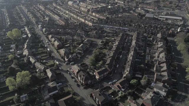 Aerial view flying above suburban British housing rooftops at sunrise golden hour tilt up to skyline