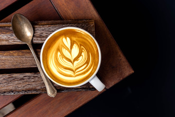 White cup of latte art barista cappuccino on a wooden table