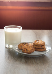 Chocolate chips cookies on plate with milk.