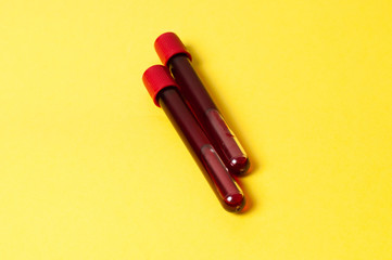 Two test tubes with blood isolate on yellow background. Concept medicine, the fight against viruses and bacteria, diseases