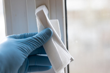 Male hand in a medical glove sterilizes a window handle.