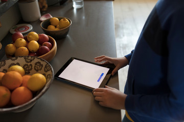 a beautifull teenager using tablet in kitchen 