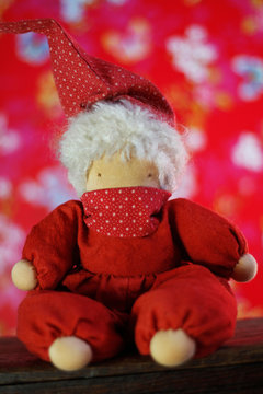 selbstgemachte Walddorfpuppe, Schlamperle mit Mundschutz, Schutzaske zum Schutz vor Corona, vor bunter Wand.