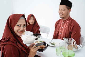 Muslim woman sit and smile when looking at camera. Asian family enjoy eating together when breaking fast at home