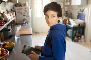 a beautifull teenager using tablet in kitchen 