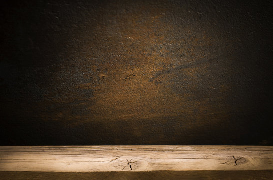 Old table top with brown concrete block wall in dark room background.