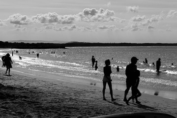 Fototapeta na wymiar Nossa heads sunshine coast australia queensland. silhouettes of people on the beach at sunset. crowded beach, father with his two children entering the sea water Siluet