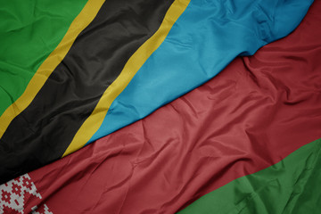 waving colorful flag of belarus and national flag of tanzania.