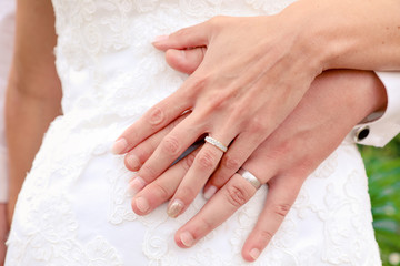 Obraz na płótnie Canvas Alliances en or, diamant et argent. Mains du couple sur la robe de mariée lors d'un mariage champêtre. Célébration de l'amour dans la nature.