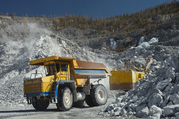 Heavy mining dump truck inside a limestone quarry, close-up. Heavy mining equipment.