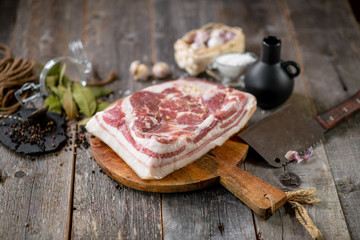 Salted brisket with spices on wooden board with garlic pepper jar wooden