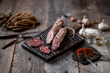 Beef jarky sausage with spices on wooden board with garlic pepper jar wooden