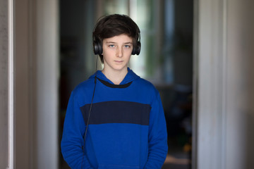 portrait of a tennager with headphones in his room standing and looking straight