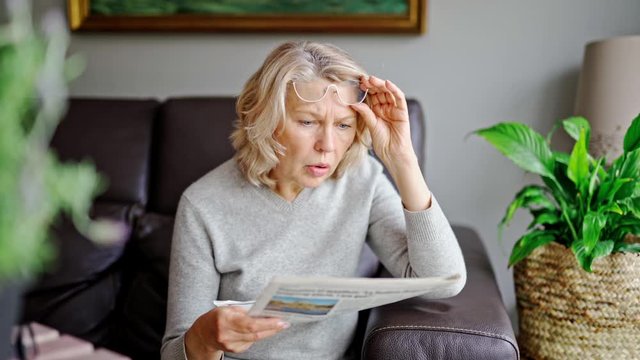 Shocked,woman reading newspaper bad news