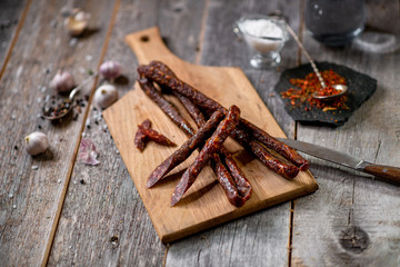 Sausage beef jarky on wooden board with pepper garlic salt spices spoon