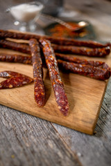 Sausage beef jarky on wooden board with pepper garlic salt spices spoon