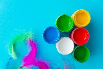 colorful paint buckets on a colorful background and bird feathers
