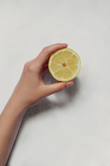 Hand holding lemon isolated on white background. Woman's hands with a piece of lemon.