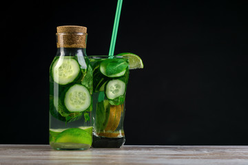Citrus fruit and herbs in glass on wooden board, dark background