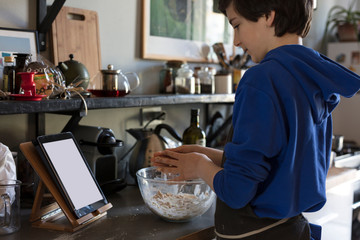 teenager following on a tablet instructions to cook