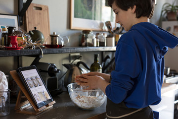 teenager following on a tablet instructions to cook