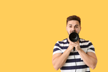 Handsome young man with blow dryer on color background