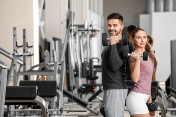 Fototapeta na wymiar Sporty young couple training with dumbbells in gym