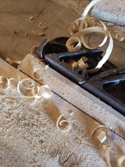 an old wood plane made of metal on a wood background with curls of wood