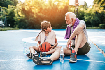 Grandfather and his grandson enjoying together on basketball court.