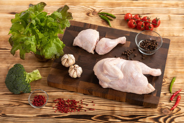 Raw chicken and vegetables on a wooden cutting board