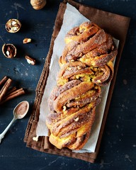 Cinnamon twisted loaf bread or babka on a dark wooden background, still life, rustic style