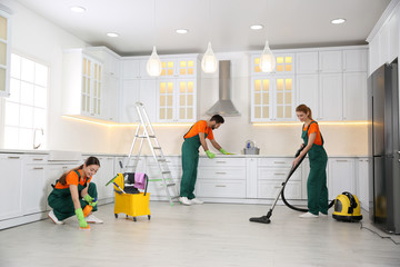 Team of professional janitors cleaning modern kitchen