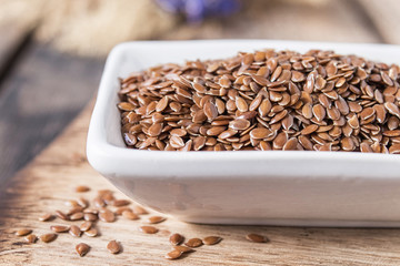 Flax seeds in a white bowl on a wooden table.