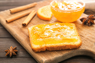Tasty orange jam with toasted bread on table
