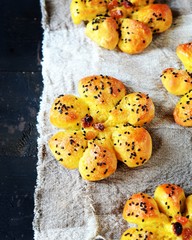 Homemade buns with raisins and sesame seeds on a dark wooden background