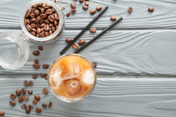 Glass of tasty iced coffee on grey wooden background